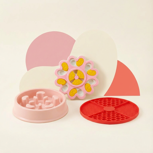 Pink Pawmimi slow feeder bowl, pink puzzle feeder toy with yellow tabs, and red calming lick mat arranged on a warm pastel background for pets.
